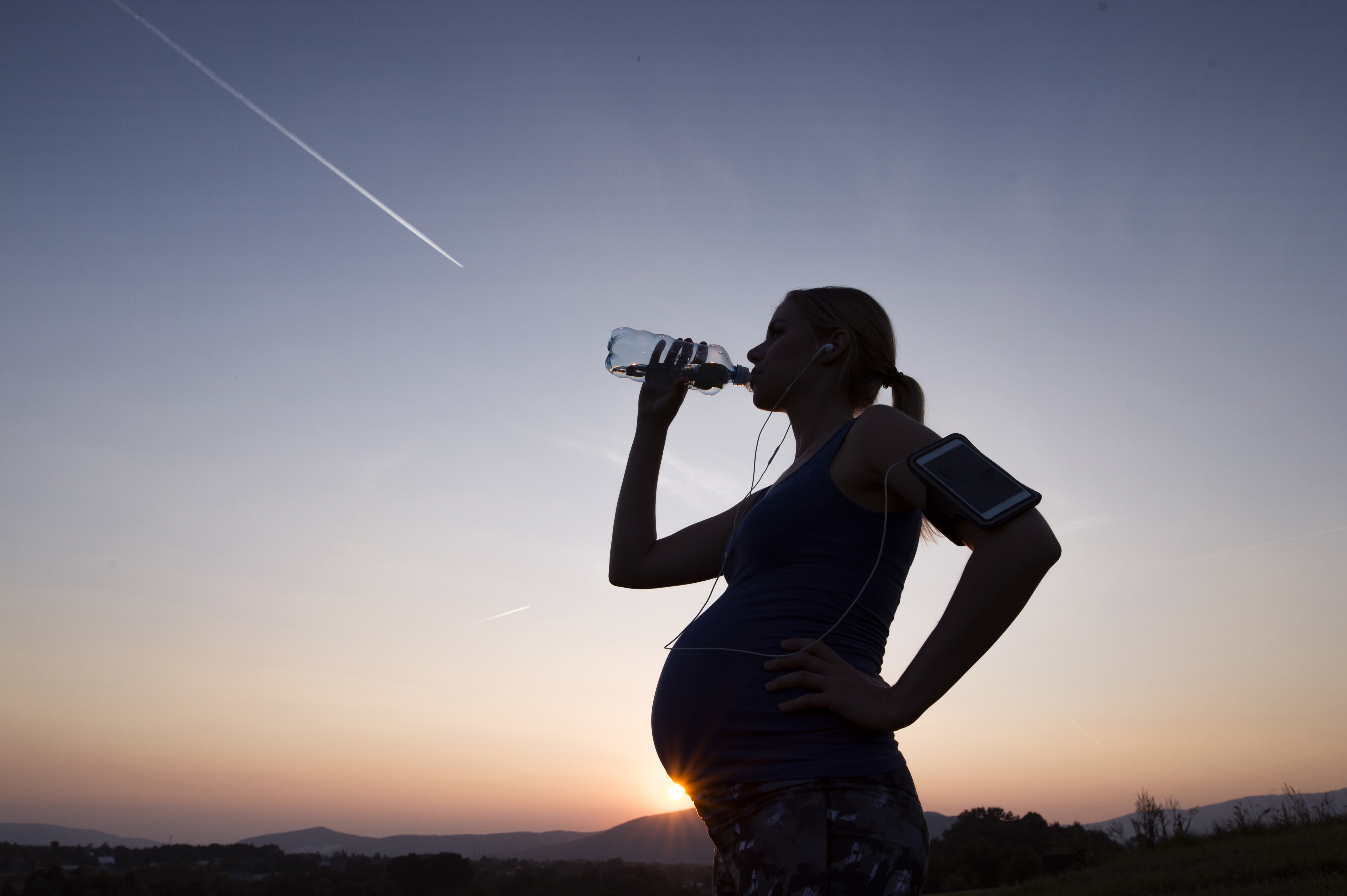 Une femme enceinte qui boit de l'eau après avoir fait un jogging